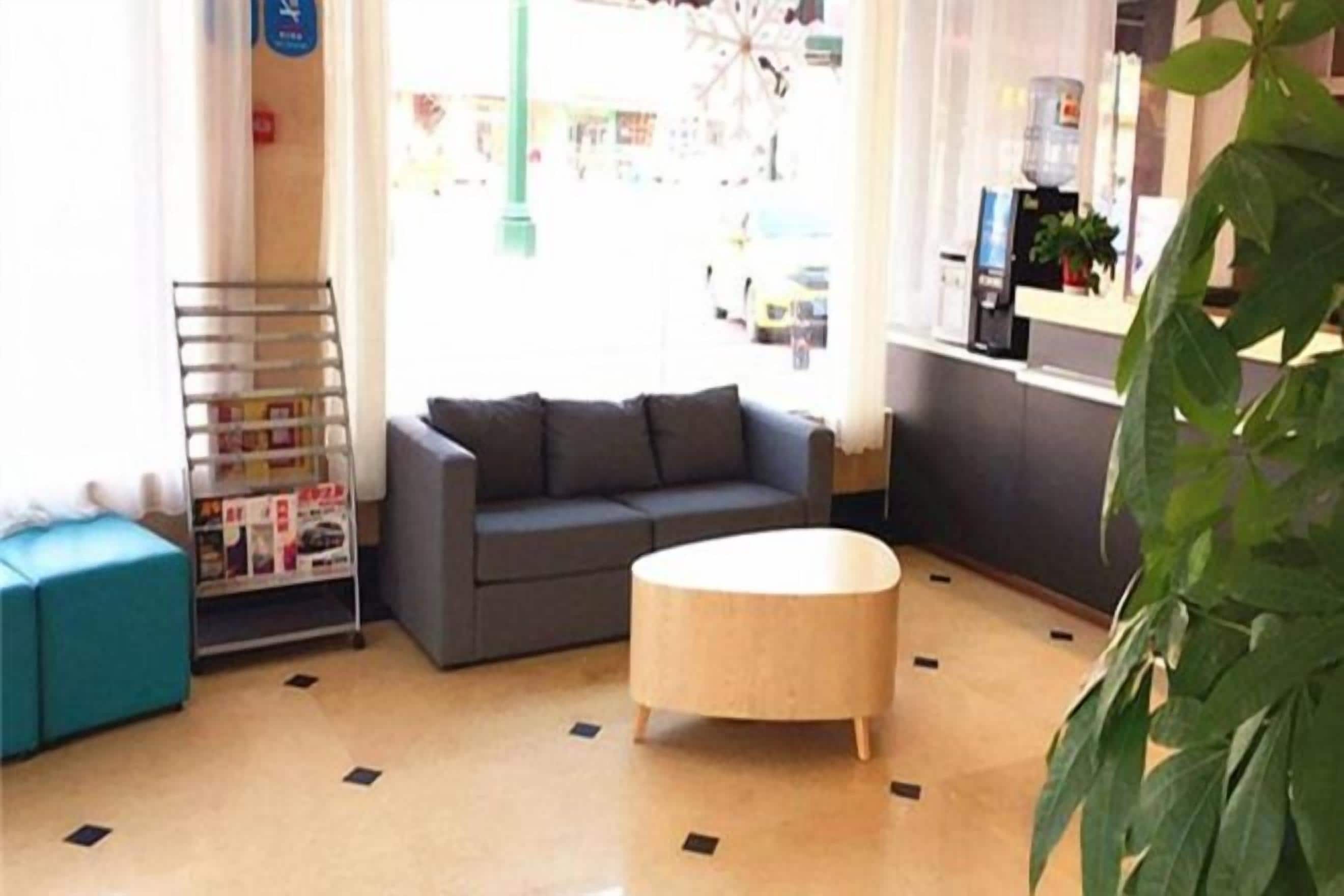 A room with a sofa, a round table, and a plant.