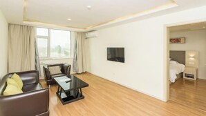 A modern hotel room with a sofa, a small table, a TV, and a bed with a nightstand. - Huamei Hotel (Linyi Luozhuang District Government) (Linyi)