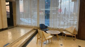 A hotel lobby with a seating area, large windows, and a view of the street. - Huamei Hotel (Linyi Luozhuang District Government) (Linyi)