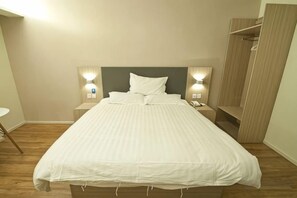 A neatly made bed with a headboard, bedside lamps, and a telephone on a bedside table. - Huamei Hotel (Linyi Luozhuang District Government) (Linyi)