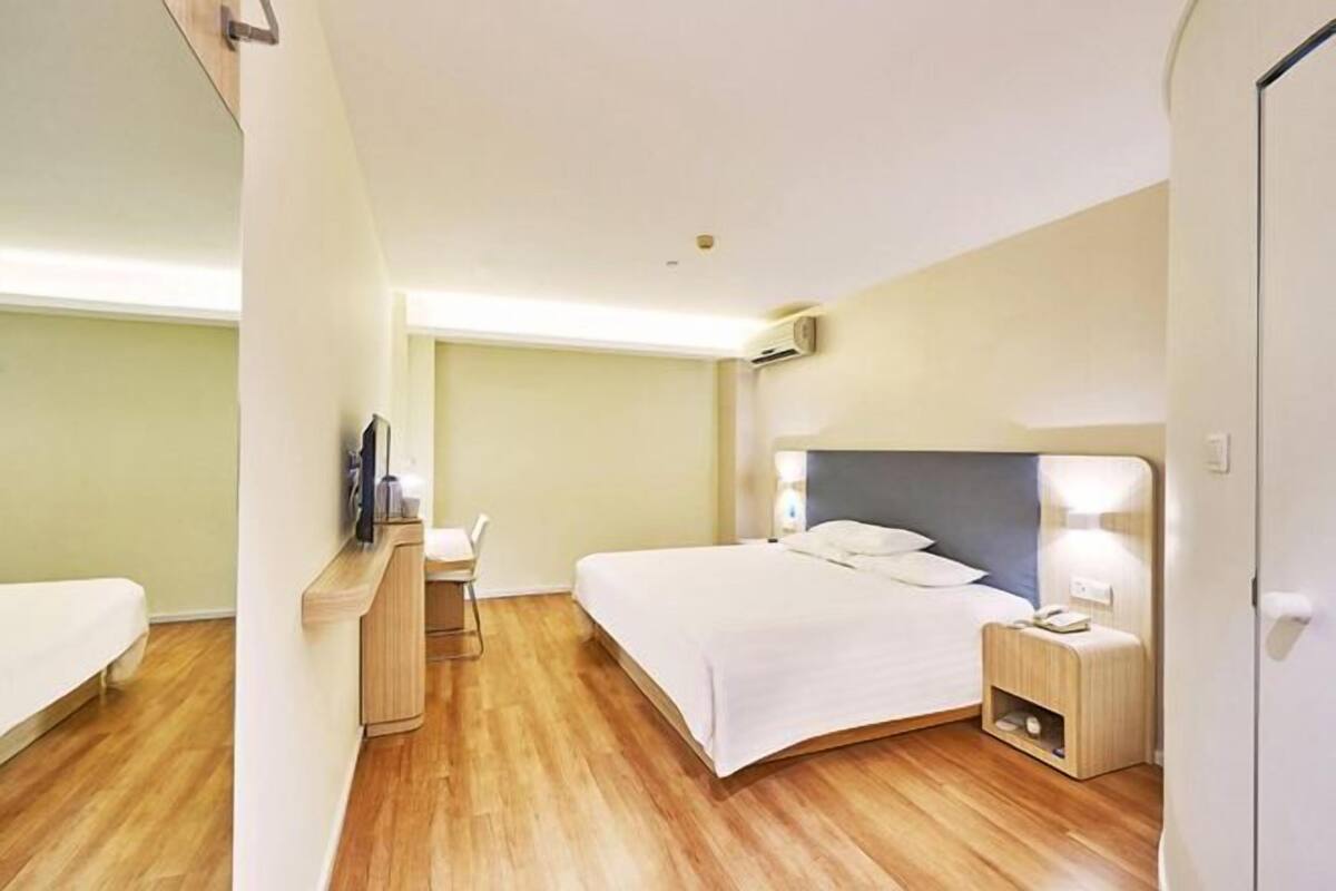 A hotel room with a bed, bedside table, and a desk with a chair.