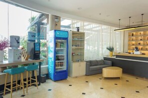 Een moderne hotellobby met een zithoek, een blauwe minibar en een receptiebalie.