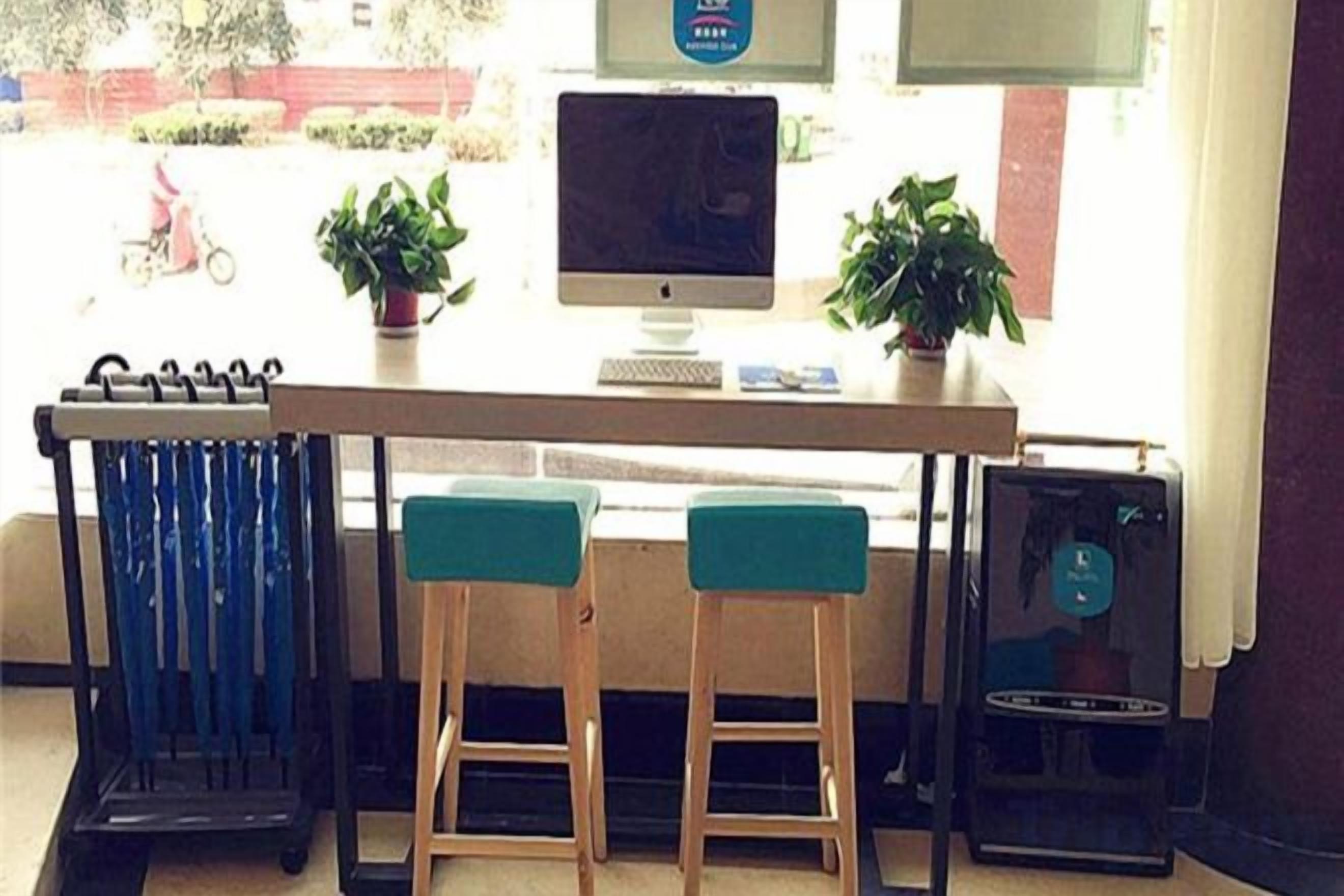 A bar area with two stools, a computer monitor, and a small table.