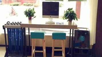 A bar area with two stools, a computer monitor, and a small table.