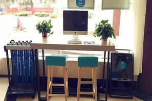 Een bar met twee krukken, een computerscherm en een kleine tafel.