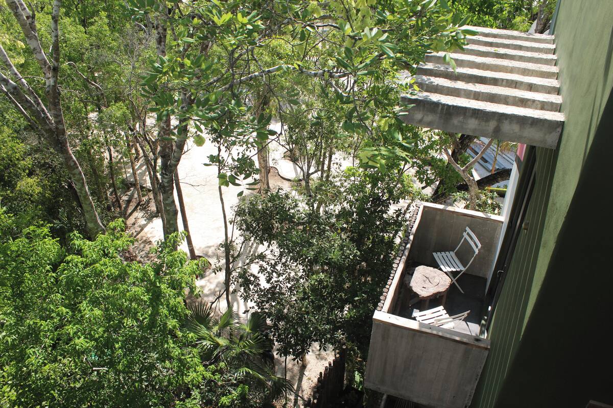 A balcony with a view of a garden and a small table with chairs.