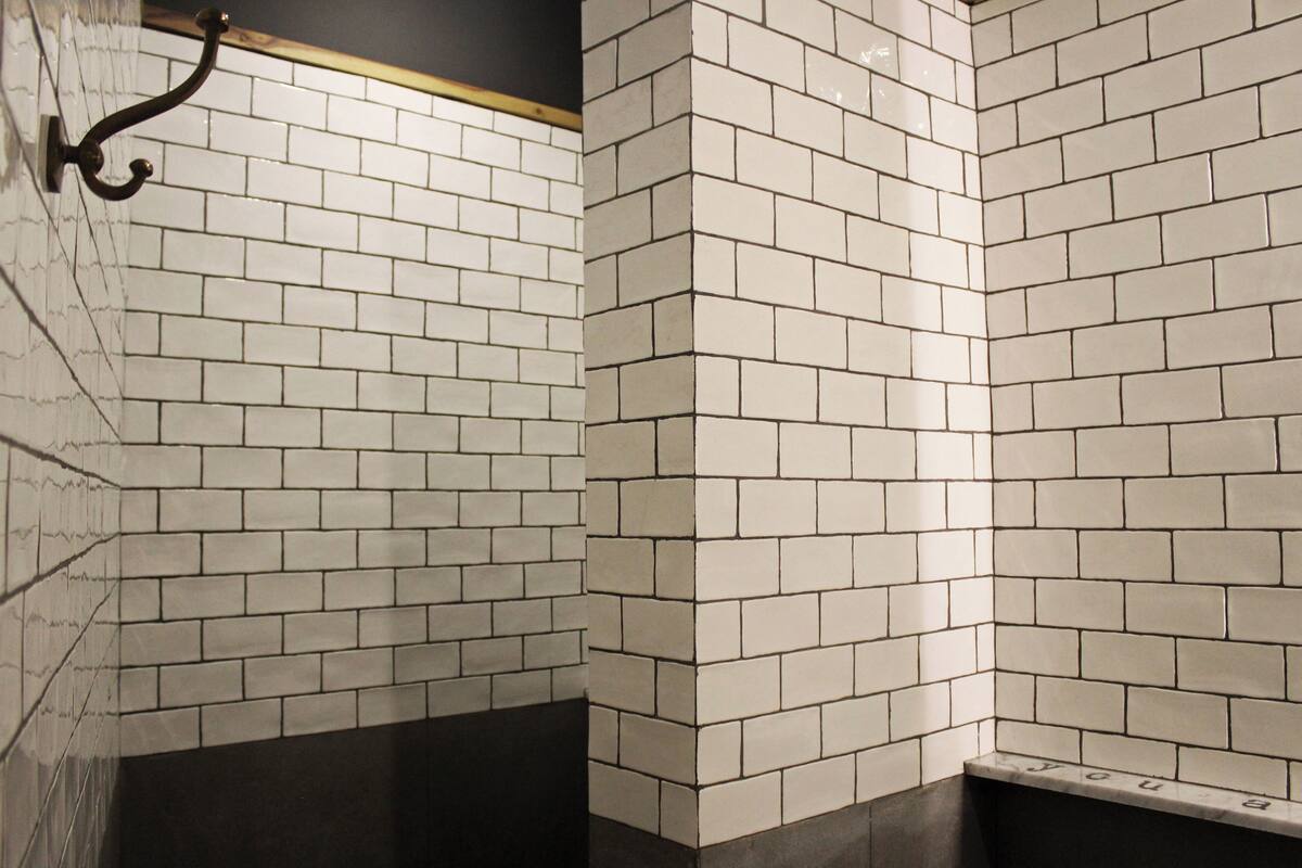 A corner of a room with white tiled walls and a dark floor.