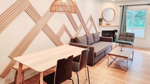 A modern living room with a wooden dining table, a sofa, and a coffee table. - The overlook stay - Free parking - 26 (Harvie Heights)