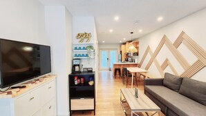 A modern living room with a flat-screen TV, a coffee station, and a dining area with a wooden table and chairs. - The overlook stay - Free parking - 26 (Harvie Heights)
