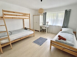 Um quarto com beliches, uma escrivaninha e uma cadeira.