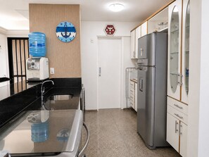 Eine moderne Küche mit einem Edelstahlkühlschrank, einem Wasserspender und einer Wanduhr mit Ankerdesign.