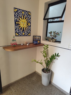 A corner of a room with a wooden shelf displaying a framed picture, a small Christmas tree, and a potted plant. - APT 3 suites: Cond Aquaville - 1 km from Beach Park (Aquiraz)