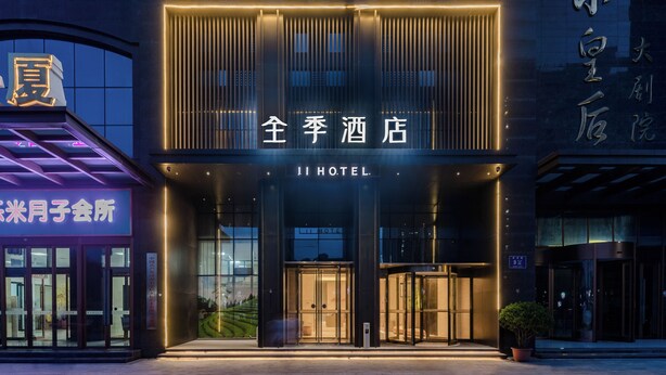 L’entrée d’un hôtel, avec une façade moderne, un éclairage décoratif et une porte tournante.