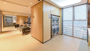 Une chambre d’hôtel moderne dotée d’une grande fenêtre, d’un lave-linge et d’un sèche-linge intégrés, et d’un miroir qui reflète la pièce.