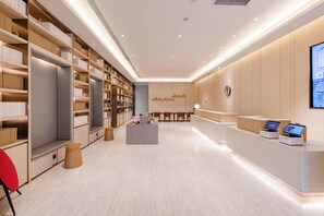 A modern interior with a reception desk, seating area, and bookshelves. - Ji Hotel (Zhengzhou)