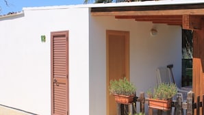 A small building with a wooden door and a window, surrounded by a wooden fence and potted plants. - Green Garden eco holiday (Vieste)