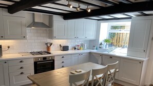 A modern kitchen with white cabinets, a wooden table, and a window overlooking a garden.
