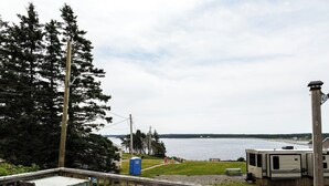 Une vue sur un lac, avec une terrasse en bois, des toilettes portables et des camping-cars en arrière-plan.