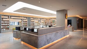 Uma biblioteca moderna com um balcão de recepção central, estantes de livros e um interior limpo e bem iluminado.