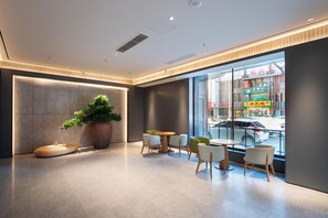 A modern interior with a reception desk, seating area, and large windows offering a view of the street. - Ji Hotel (Shenyang)