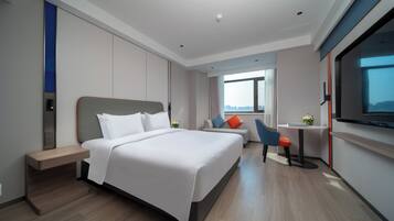 A modern hotel room with a large bed, a desk, and a TV.