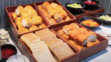 Une table de buffet proposant divers plats, notamment du pain, des salades et des sauces.