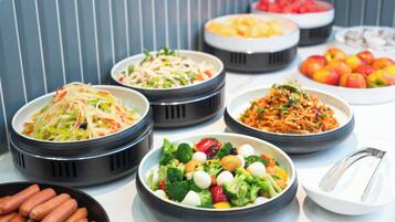 Un bufé con diversos platos, incluyendo ensaladas, frutas y verduras.