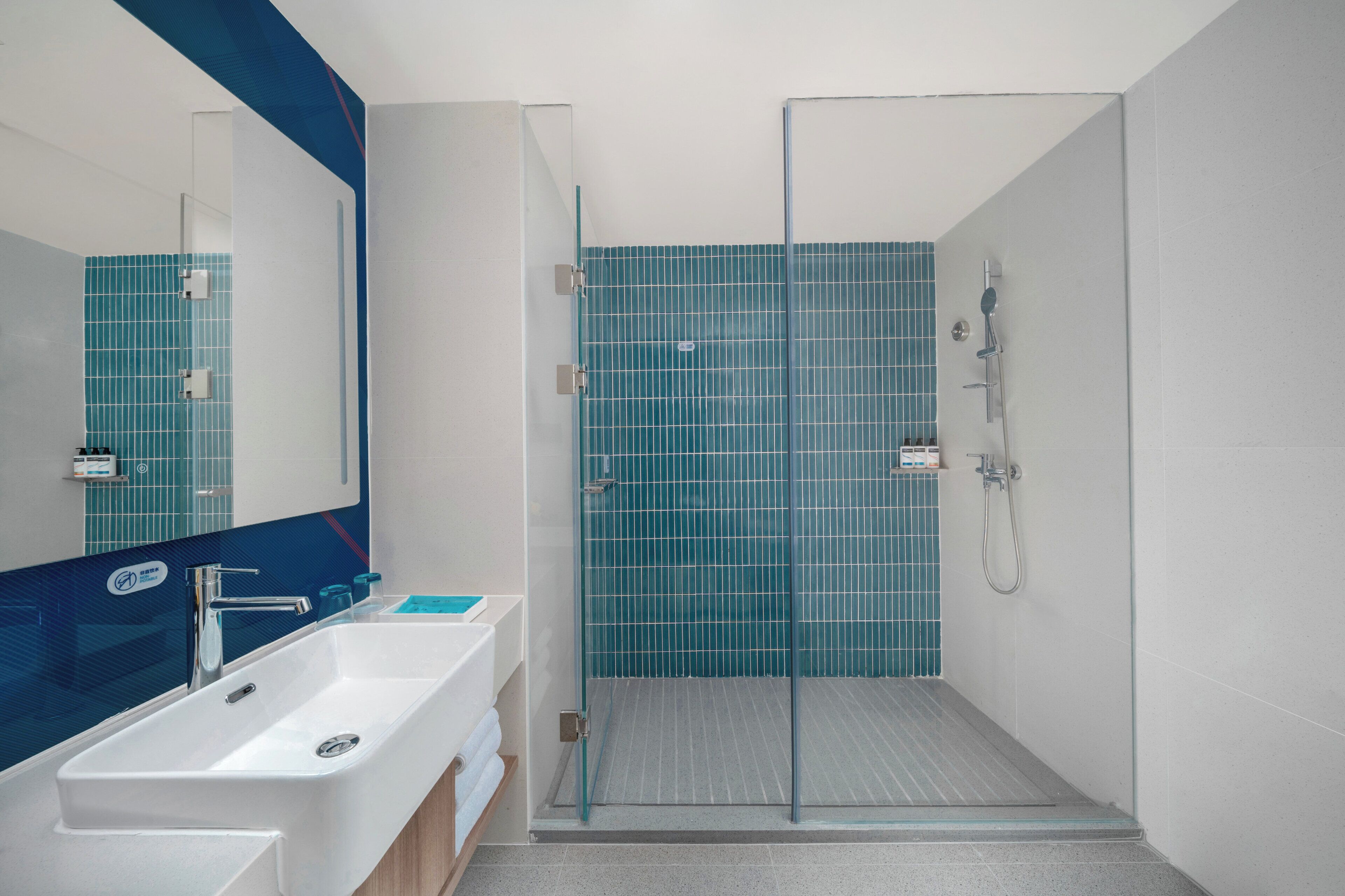 A bathroom with a white sink, a mirror, and a shower area with a glass door.