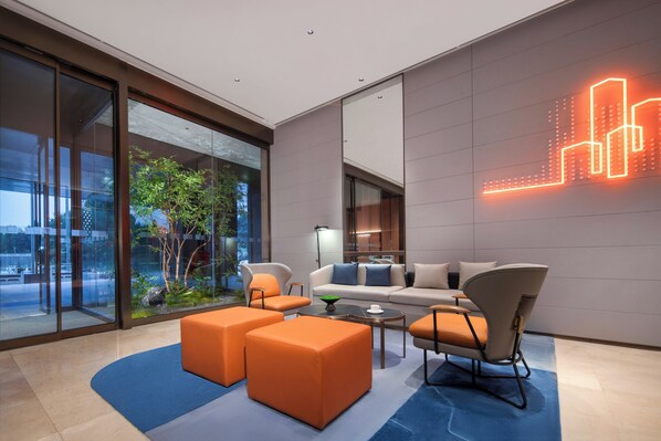 A modern living room with a sofa, ottomans, and a coffee table. - Holiday Inn Express Zhengzhou Garden Road by IHG (Zhengzhou)