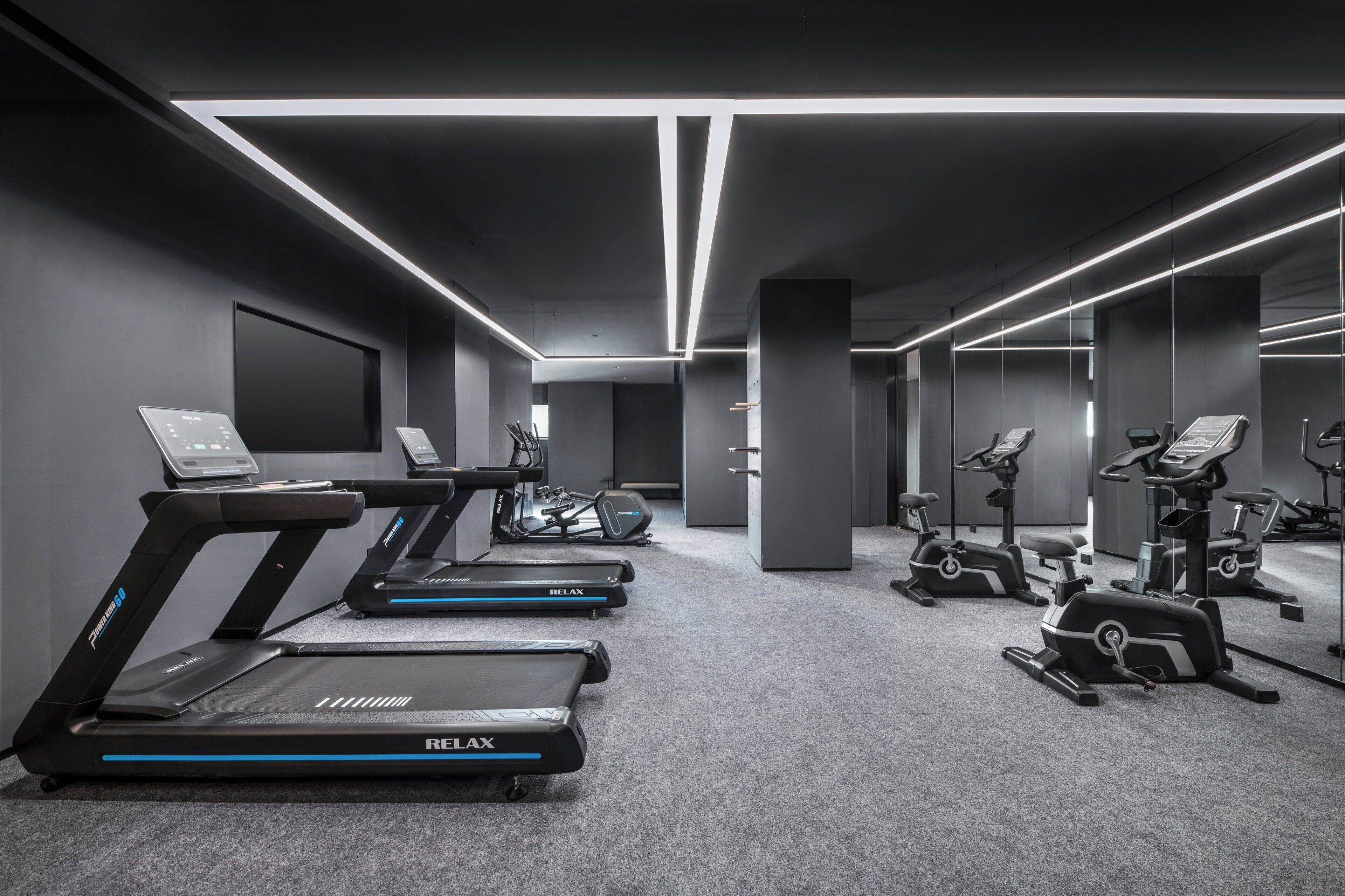 A modern gym with multiple treadmills, stationary bikes, and elliptical machines.