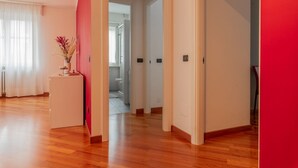 A modern interior with a wooden floor, a white reception desk, and a red accent wall.