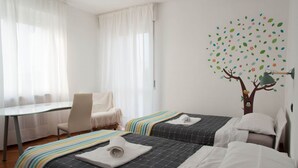 A hotel room with two beds, a desk, and a chair.
