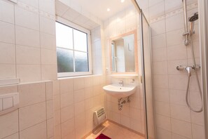 Un baño con ventana, lavamanos y ducha.