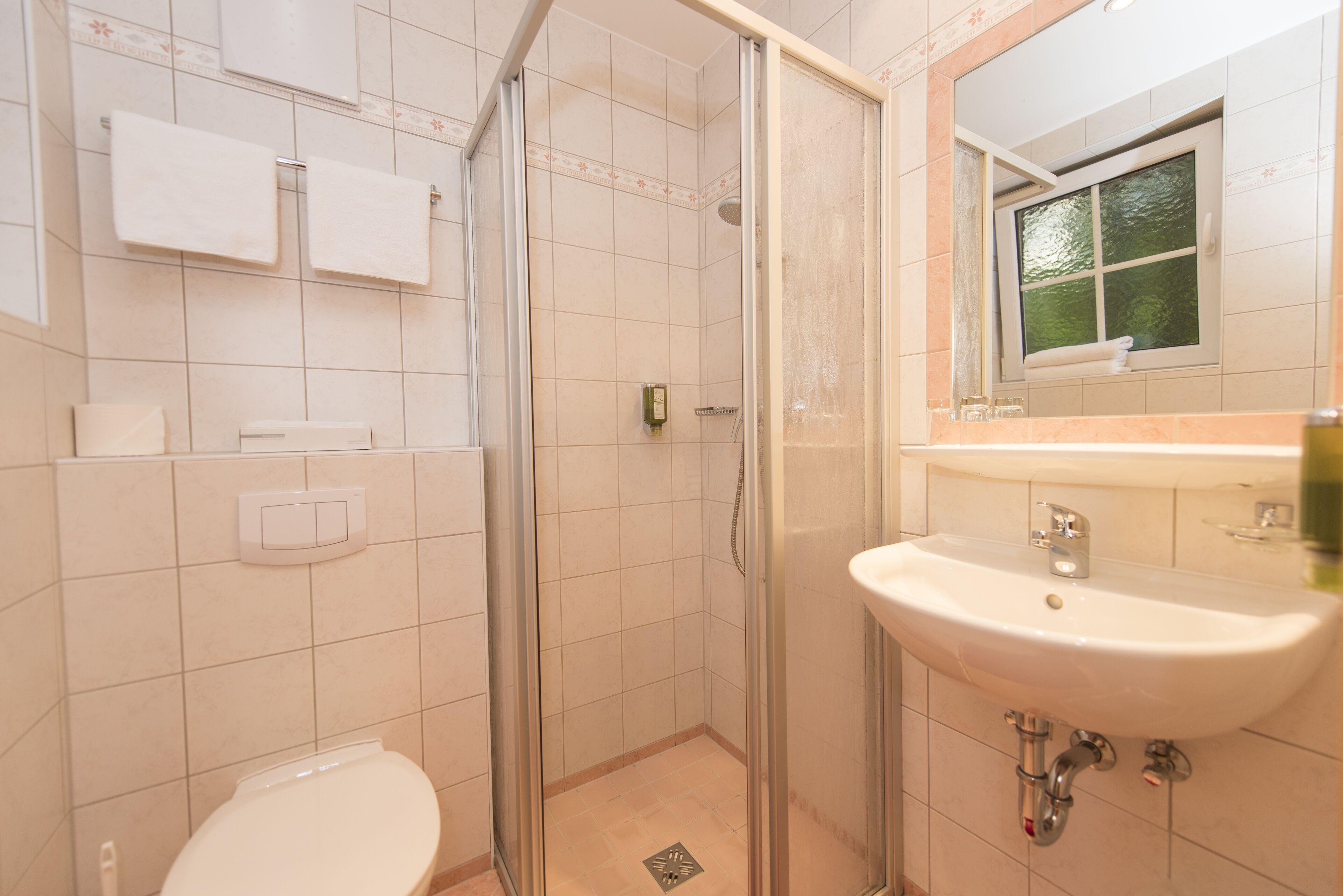 A bathroom with a toilet, a shower, and a sink.
