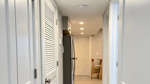 Ein Flur mit weißen Türen, einem Kühlschrank und Holzdielen.