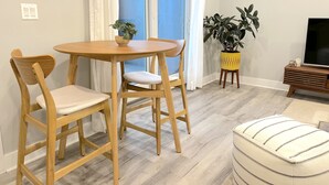Ein Essbereich mit Holztisch und -stühlen, einem Blumentopf und einem Fernseher auf einem Holzgestell.