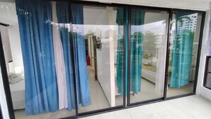 Quarto com porta de vidro deslizante, piso de azulejos e vista para uma área residencial.