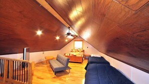 A cozy attic bedroom with a wooden ceiling, a bed, a sofa, and a small seating area. - Tranquil Cabin on Barren River Lake (Glasgow)
