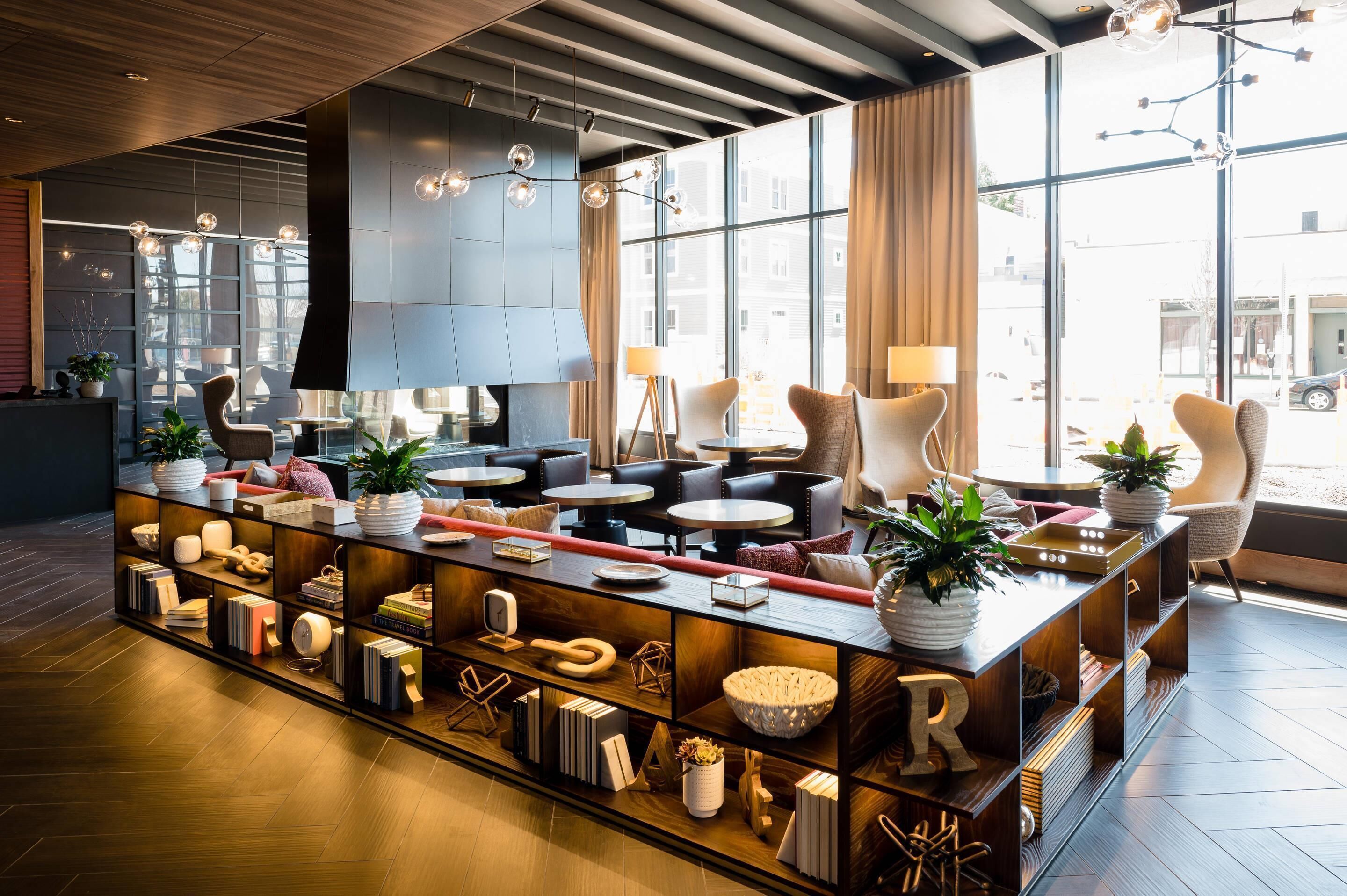 Zona de bar moderna con una barra larga, diversas opciones de asientos y grandes ventanales con vistas al exterior.
