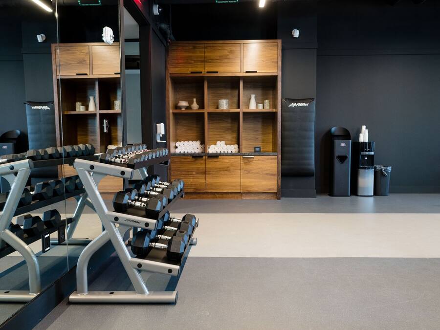 A gym with weightlifting equipment, wooden cabinets, and a water dispenser.