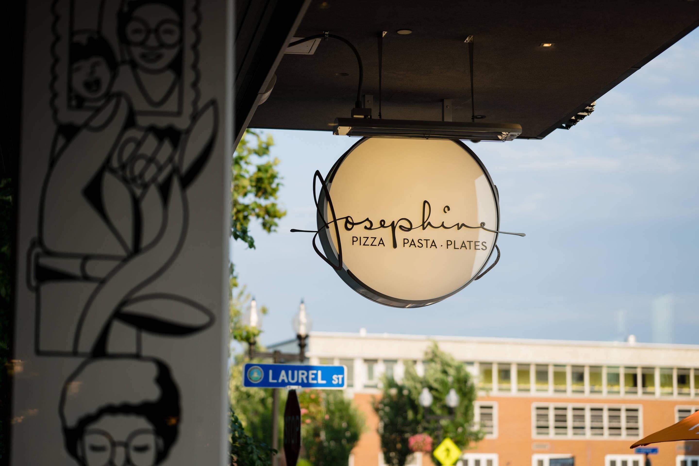 Un letrero de restaurante con el nombre 'Josephine Pizza Pasta Plates' y una señal de calle que indica 'Laurel St'.