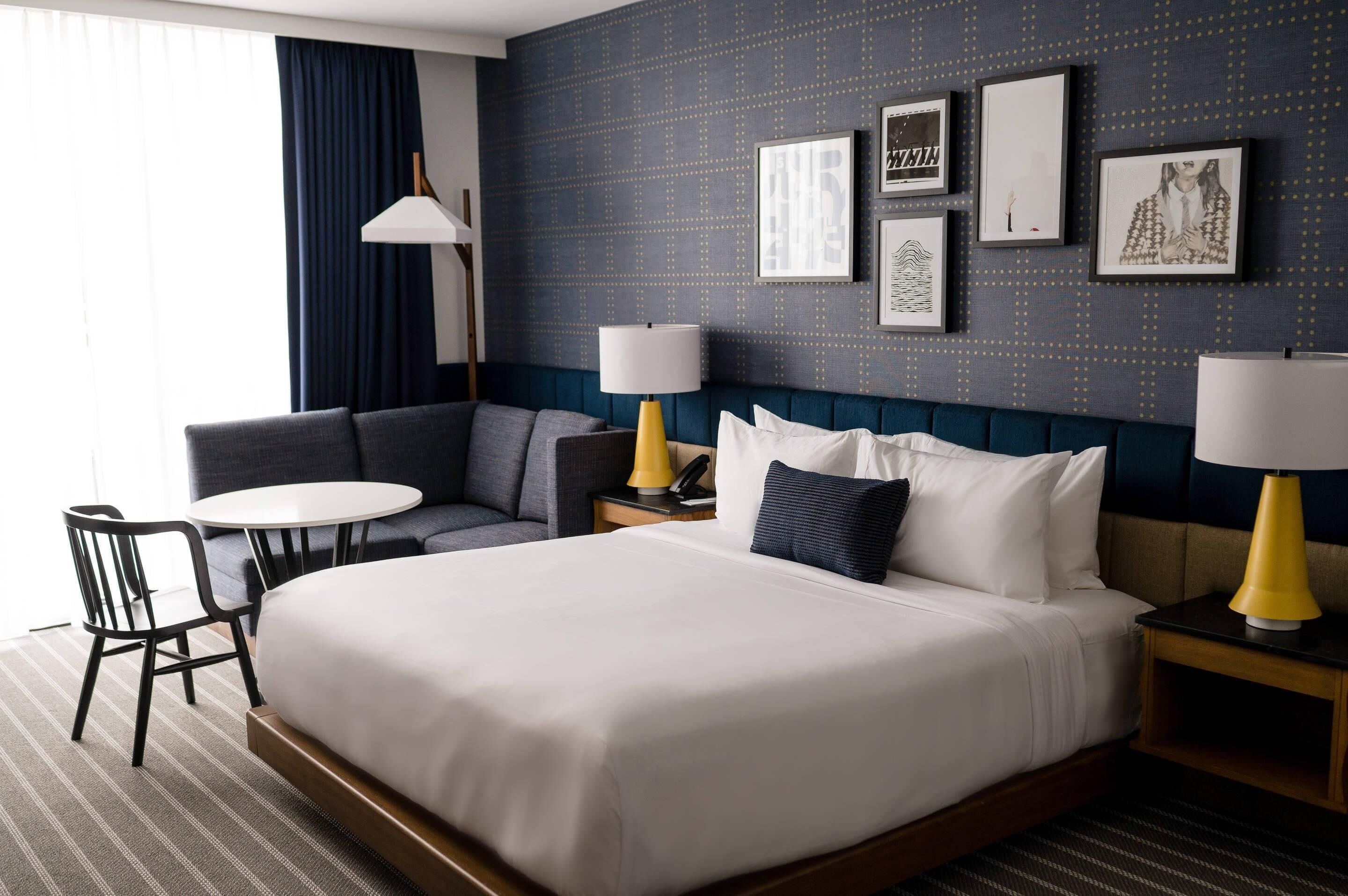 Una habitación de hotel con una cama grande, un sofá, una mesita y dos lámparas.