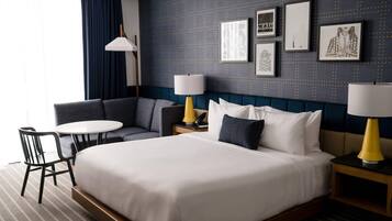 Una habitación de hotel con una cama grande, un sofá, una mesita y dos lámparas.
