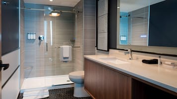 Ein modernes Badezimmer mit Duschkabine aus Glas, Toilette, Waschtisch mit Spiegel und Waschbecken.