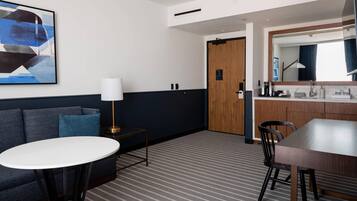 Habitación de hotel con sofá, una mesa redonda, una cafetera y un espejo.