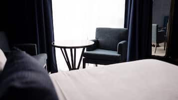 A hotel room with a bed, a small round table, and two armchairs.