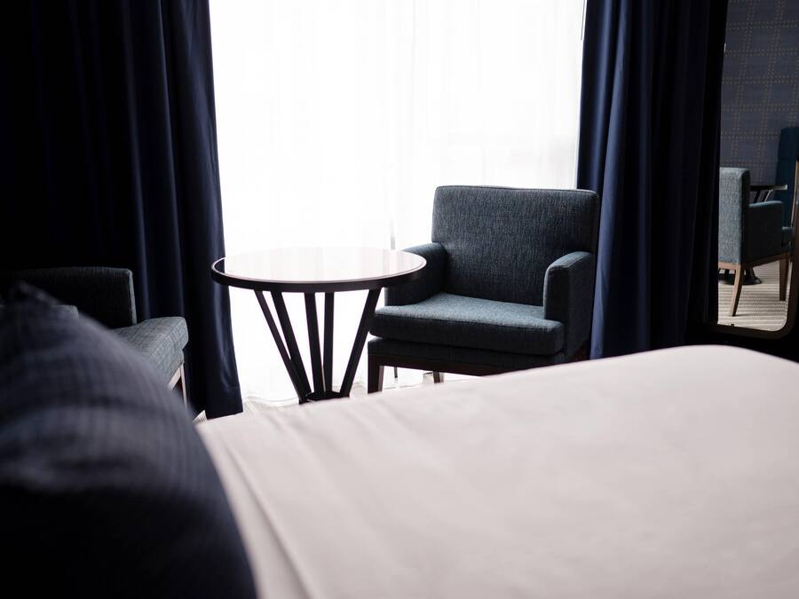 A hotel room with a bed, a small round table, and two armchairs.