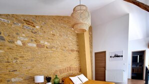A bedroom with two beds, a stone wall, a wooden floor, and a hanging light fixture. - Loft in the heart of the vineyards in a former Chai dating from 1815 (Marcy)