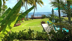 Un giardino tropicale con palme, una piscina e vista sull'oceano.