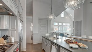 Een moderne keuken met witte kasten, roestvrijstalen apparatuur en een groot eiland met een spoelbak en een eethoek.
